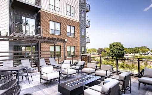 A patio with a table and chairs is in front of a brick building.