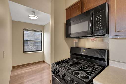 A black microwave is mounted above a black stove in a kitchen.