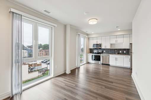 A modern kitchen with white cabinets and a wooden floor.