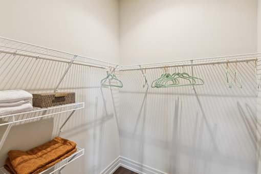 A white closet with clothes hanging on hangers.