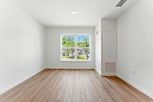 A room with a large window and wooden flooring.