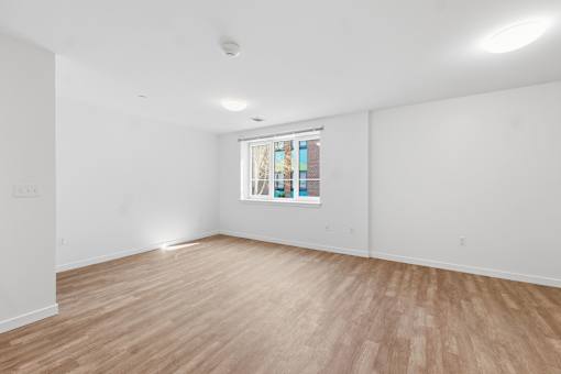 A room with wooden flooring and a window with a stained glass design.