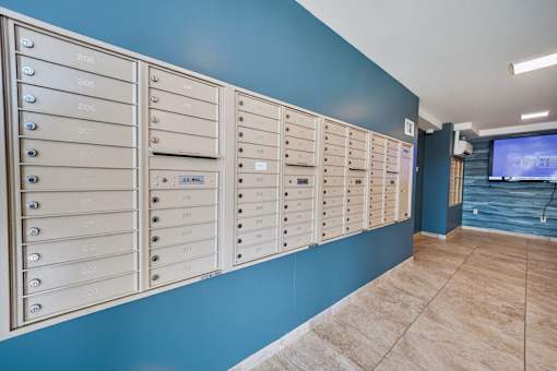A row of mailboxes are lined up against a blue wall.