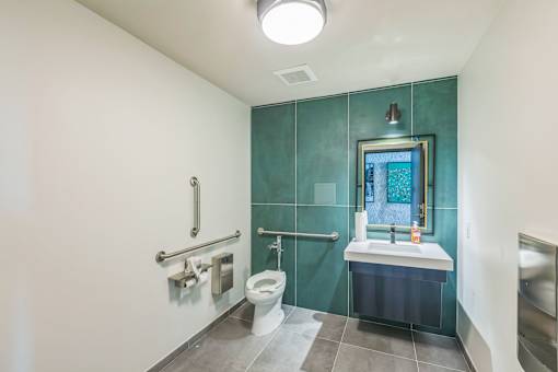 A bathroom with a toilet, sink, and mirror.