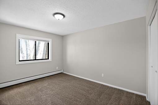 A room with a window and carpeted floor.
