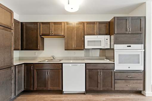 A kitchen with brown cabinets and a white dishwasher.