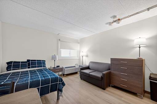 A bedroom with a bed, a couch, and a nightstand.