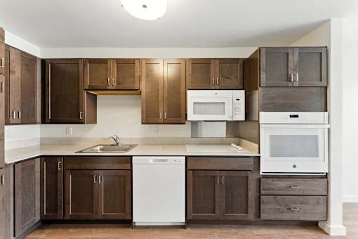 A kitchen with brown cabinets and a white dishwasher.