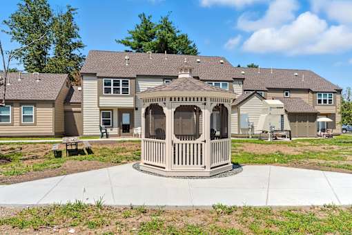 A gazebo is in the middle of a concrete walkway in front of apartment buildings.