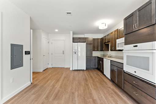 A kitchen with white appliances and wooden floors.