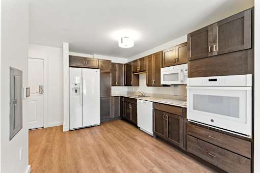 A kitchen with white appliances and wooden cabinets.