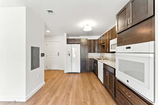 A modern kitchen with white appliances and wood floors.