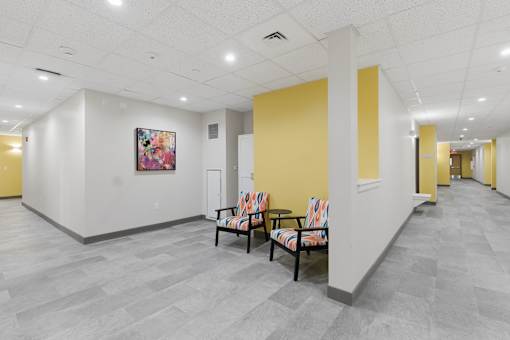 A hallway with a yellow wall and a painting on the wall.