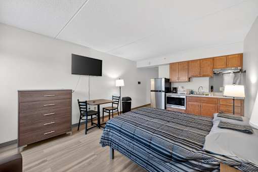 A bedroom with a bed, a table and chairs, and a television.