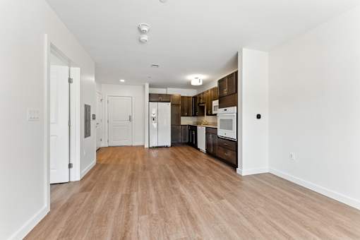 A kitchen area with white cabinets and a wooden floor.