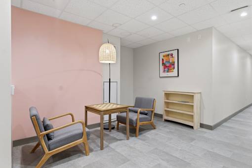 A room with a pink wall and a wooden chair.