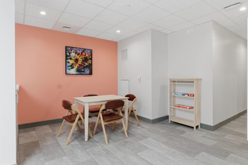A room with a table and chairs and a bookshelf.