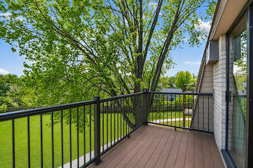 A balcony with a black railing and a wooden floor.