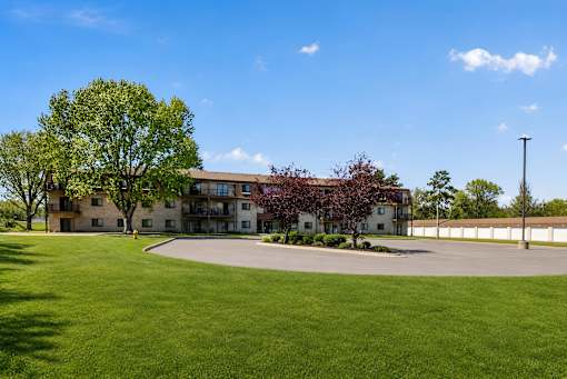 A large grassy area in front of a building with a tree on the left.