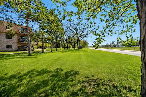 A grassy field with trees and a building in the background.