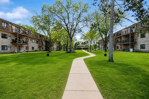 A walkway leads through a grassy area between apartment buildings.