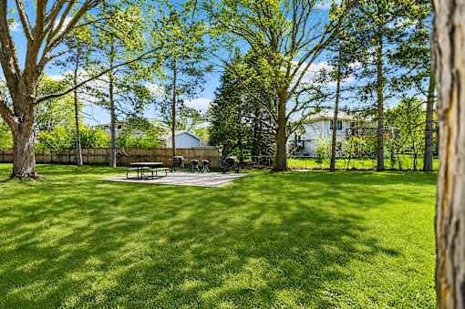A park with a picnic table surrounded by trees.