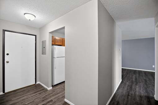 A white door is on the left of a kitchen area.