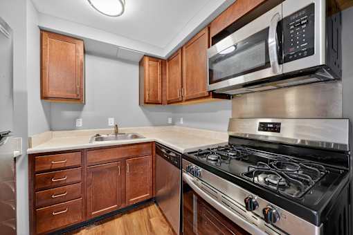 A modern kitchen with a stove, microwave, and wooden cabinets.