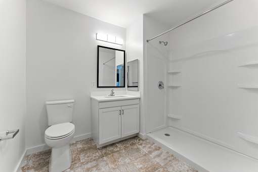 A white bathroom with a toilet, sink, and mirror.