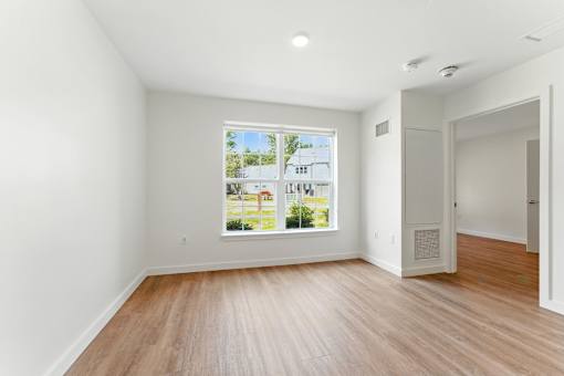 A room with a large window and wooden flooring.