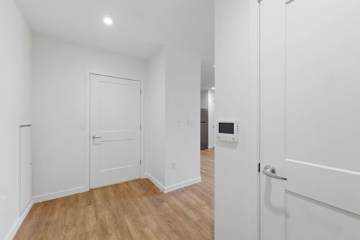 A white door is open to a room with wood flooring.