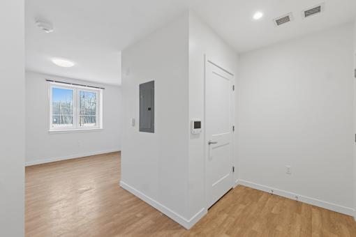 A white door is in a room with wood floors and a window.