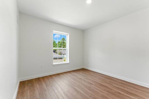 A room with a window showing a view of a house and trees.