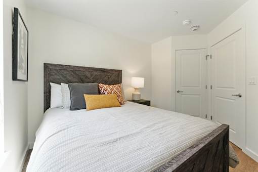 A bedroom with a large bed and a lamp on a side table.