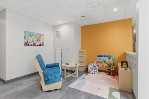 A room with a blue chair and a painting on the wall.