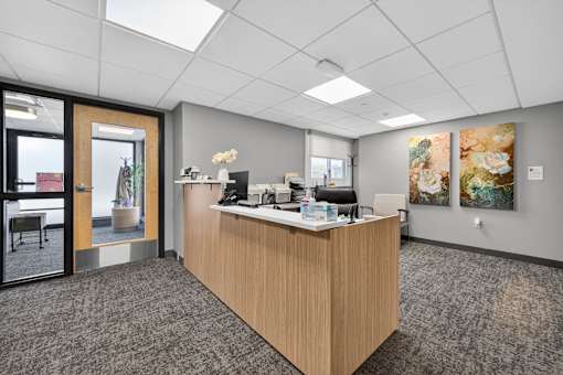 A reception area with a wooden desk and a chair.
