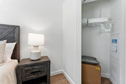 A bedroom with a bed, nightstand, and a closet with shelves.