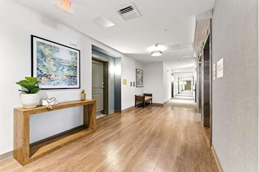 A hallway with a wooden bench and a framed picture on the wall.