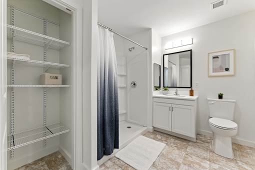 A white bathroom with a walk in shower and a toilet.