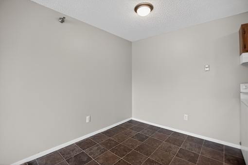 A room with a brown tile floor and white walls.