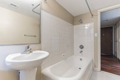 A white sink is on the left of a white bathtub in a bathroom.