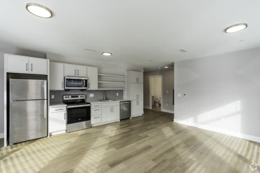 an empty kitchen with white cabinets and stainless steel appliances