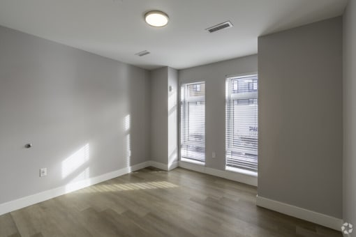 an empty living room with a large window and wood floors