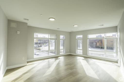 the living room of an empty apartment with large windows