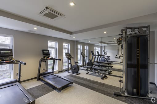 a gym with cardio equipment and windows in a building