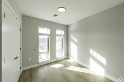 the living room of a house with white walls and wooden floors