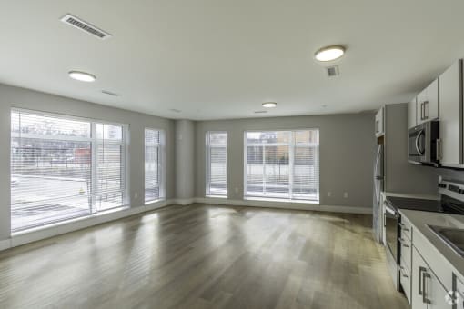 an empty kitchen with a large window and wood floors