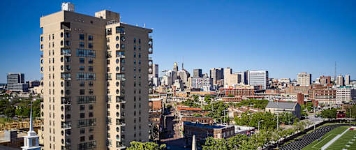 A tall building with many windows is in the foreground of a cityscape.