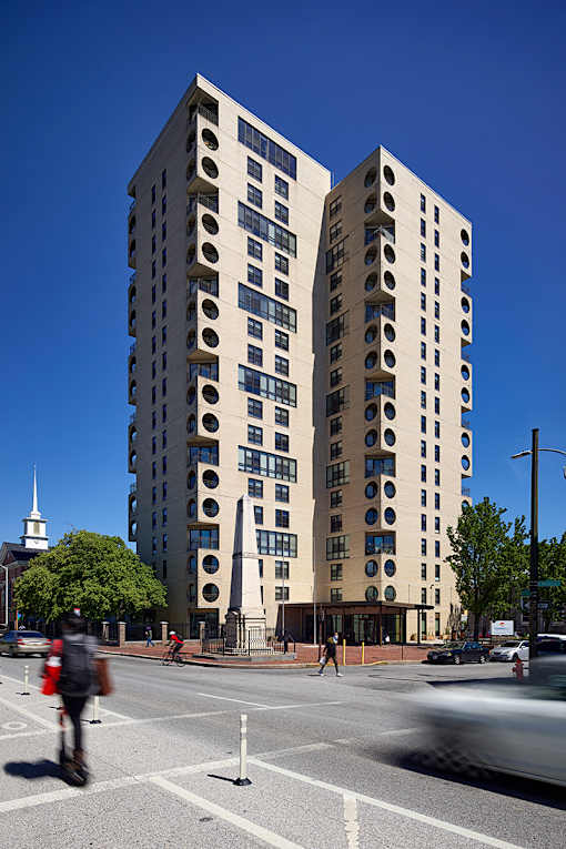 A tall building with circular windows is located on a street corner.