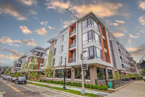 A modern apartment building with a parking lot in front.